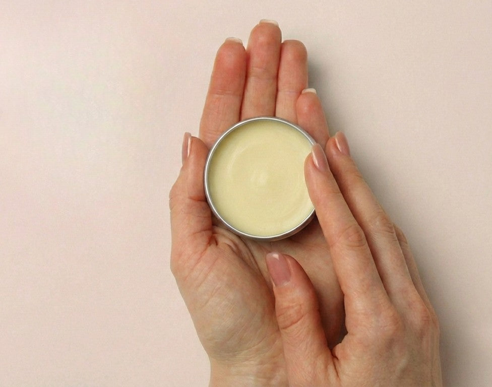 Hand holding a small tin of Matylda Baby nappy rash cream balm for easy changing bag use